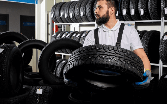 Mechanic holding a tire and showing wheel tires at car repair service Mechanic holding a tire and showing wheel tires at car repair service